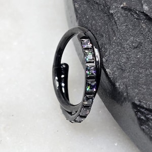 May include: Black hoop earring with a row of clear iridescent cubic zirconia stones.