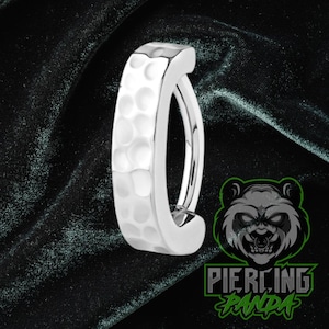 May include: A silver-colored, hammered-texture belly button ring. The ring has a curved design with a hammered texture on the outer surface. The logo for Piercing Panda is in the lower right corner.
