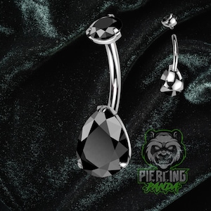 Pode incluir: Um piercing de umbigo prateado com uma grande gema preta em forma de gota e uma gema menor a condizer. O anel curvo tem um acabamento polido. Uma gema separada e o logótipo "Piercing Panda" também são visíveis.