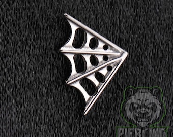 May include: A silver-toned metal jewellery piece shaped like a stylised bat wing with a webbed design. The accessory features a triangular silhouette with multiple cut-out sections and thin, raised structural lines radiating from the pointed corner.