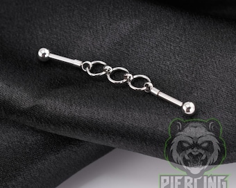 May include: A silver-toned industrial barbell piercing jewelry featuring a straight metal bar with a ball at each end and three interconnected circular rings suspended in the center of the shaft, creating a linked chain design element.