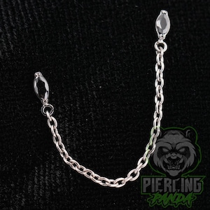 May include: A silver-toned metal chain connector featuring two marquise-cut black gemstones at each end. The chain consists of small, uniform oval links, creating a flexible bridge between the two dark, pointed stone settings for body jewelry.