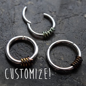 May include: Three silver-toned metal hoop rings with hinged closures. Each ring features a section wrapped in thin wire. One ring has green wire, while the other two have dark brown and black wire. The text "FEATHERBLUEJEWELRY" and "CUSTOMIZE!" appear.
