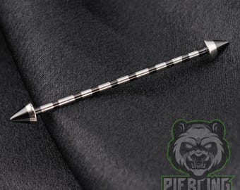 May include: A straight industrial barbell body jewelry piece featuring a long, thin metal shaft with alternating silver and black stripes. The barbell is finished with a sharp, conical spike at each end, creating a sleek and uniform appearance.