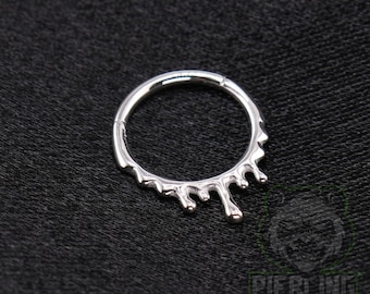 May include: A silver-coloured circular hoop ring featuring a decorative drip design along the bottom half. The metal surface is smooth and reflective, with a hinged segment visible on the left side of the hoop, creating a continuous circular shape.