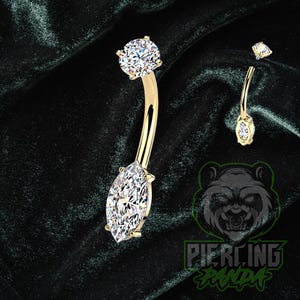 Peut inclure: Un piercing de nombril doré avec une barre incurvée. La bague présente une grosse pierre précieuse transparente de taille marquise en bas et une pierre précieuse ronde transparente en haut. Une version plus petite de la bague est également montrée.