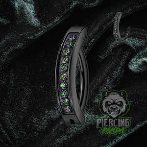 Pode incluir: Argola de nariz preta curva com uma fileira de pedras preciosas verdes e roxas iridescentes. A joia é feita de metal preto e tem um acabamento liso e polido. Uma versão menor da argola de nariz também é visível.