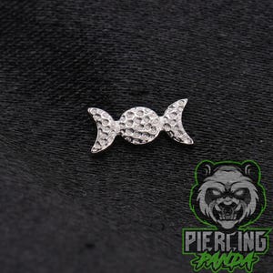 May include: A silver-toned metal body jewelry piece featuring a central circular disc flanked by two crescent moon shapes, all with a textured, hammered surface finish. The design is symmetrical and includes a logo with a panda face and the text PIERCING PANDA.