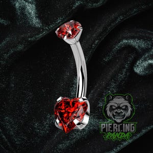 Piercing de umbigo em titânio ASTM F136 com zircônia cúbica vermelha em formato de coração, grau implante, 14g, rosca interna e cravação com garras.