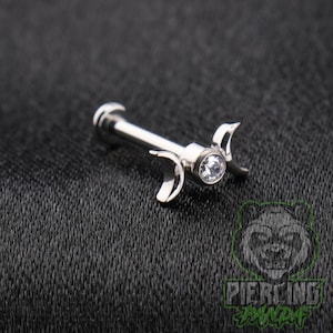 May include: A silver-toned metal labret stud featuring a central clear round gemstone set within a decorative crescent moon design. The jewelry piece includes a flat circular back disc and a straight post, showcasing a polished metallic finish.