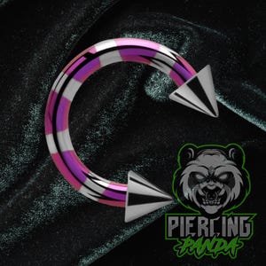 May include: A curved barbell body piercing with a striped design in pink, white, and silver. The ends are pointed, silver cones. The image includes a logo with a panda and the text "Piercing Panda".