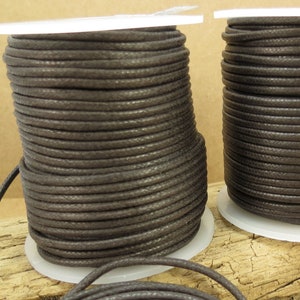 May include: Two spools of brown waxed cotton cord, each wound around a white plastic spool.