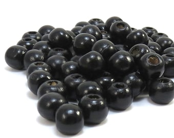 May include: A pile of black wooden beads with a hole in the center of each bead.