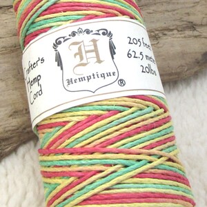 Puede incluir: Una bobina de cuerda de cáñamo multicolor en amarillo, verde y rosa. La etiqueta dice "Crafter's Hemp Cord" y "Hemptique" con el texto "205 pies, 62,5 metros, 20 libras".