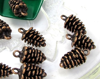 May include: A collection of 12 antique copper-toned pine cone charms. The charms are detailed and have a rustic look. They are perfect for adding a touch of nature to your jewellery or crafts.