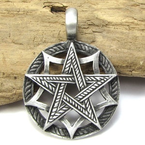 May include: A silver-toned pendant featuring a five-pointed star with intricate details. The star is surrounded by a circular frame with a rope-like design.
