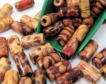 May include: A collection of wooden beads in various shades of brown and tan, with decorative patterns. Some beads have floral, geometric, or animal print designs. The beads are cylindrical and appear to be for jewelry making or crafts.