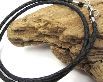 May include: A black braided leather necklace with stainless steel clasps. The necklace is displayed on a piece of driftwood against a white background. The leather appears to be tightly woven, and the clasps are shiny.