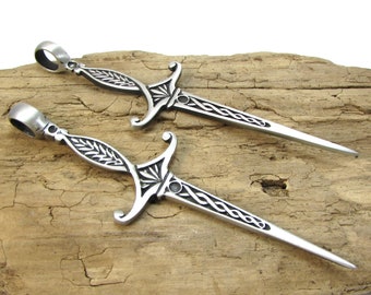 May include: Two silver-toned sword-shaped pendants with intricate designs. The pendants have a loop at the top for attaching to a chain or cord.