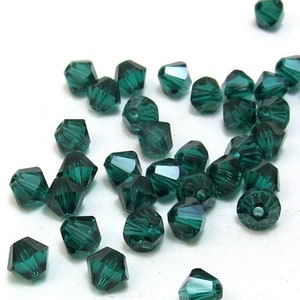 May include: A scattering of emerald green crystal beads, each with a faceted design. The beads are small and have a shiny, reflective surface.