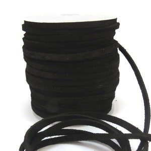 May include: A spool of black suede cord, approximately 3mm wide, is shown on a white background. The cord is wound around a white cardboard spool and a length of cord is hanging off the spool.