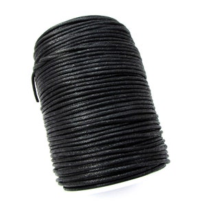 May include: A spool of black waxed cotton cord. The cord is wound tightly around the spool, creating a smooth, even surface.