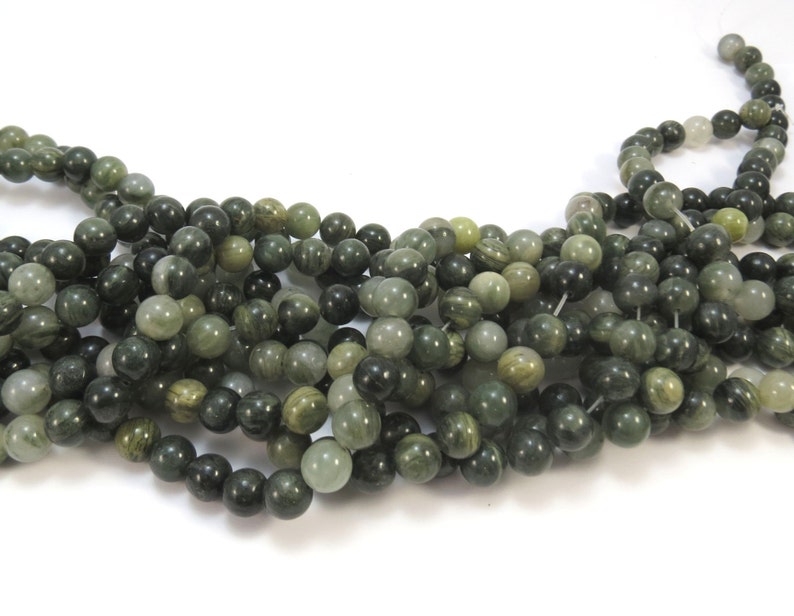 May include: A strand of green and white gemstone beads. The beads are round and have a smooth, polished finish.