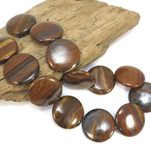 May include: A strand of round, flat, tiger's eye beads with brown, gold, and silver stripes. The beads are polished and have a glossy finish.