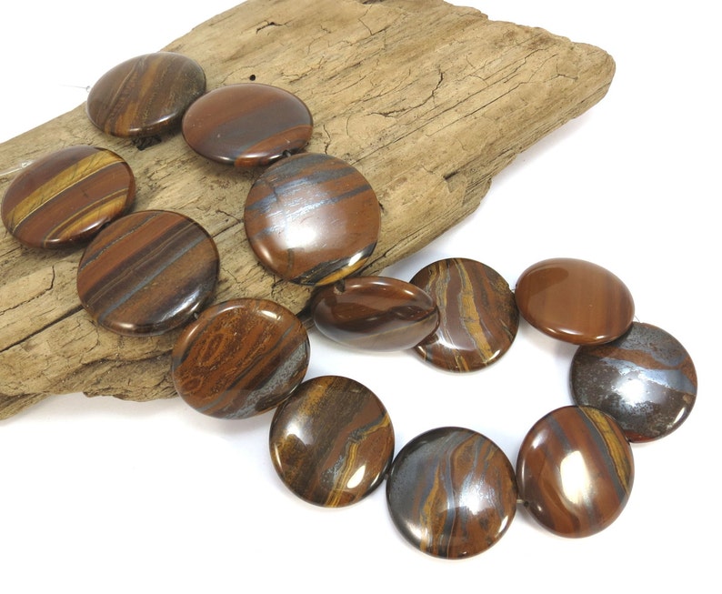 May include: A strand of round, flat, tiger's eye beads with brown, gold, and silver stripes. The beads are polished and have a glossy finish.