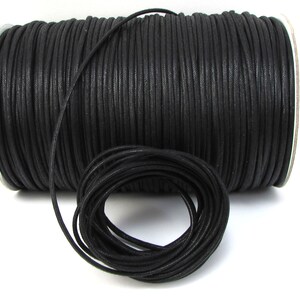 May include: A spool of black waxed cotton cord. The cord is wound tightly around the spool and is ready to be used for crafting projects.