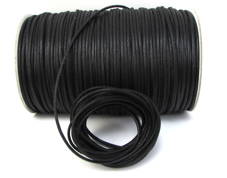 May include: A spool of black waxed cotton cord. The cord is wound tightly around the spool and is ready to be used for crafting projects.