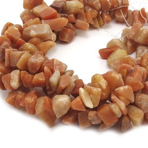 May include: A strand of orange and yellow chip-shaped gemstone beads. The beads are irregular in shape and size, and have a natural, rough texture.