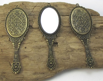 Könnte beinhalten: Drei antike Handspiegel mit verzierten Metallrahmen und einem floralen Design. Die Spiegel haben eine reflektierende Oberfläche und sind an einem dekorativen Griff befestigt.
