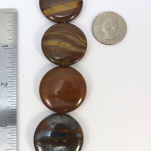 May include: A strand of round, brown and gold tiger's eye beads. The beads are approximately 2.5 cm in diameter and have a smooth, polished finish.