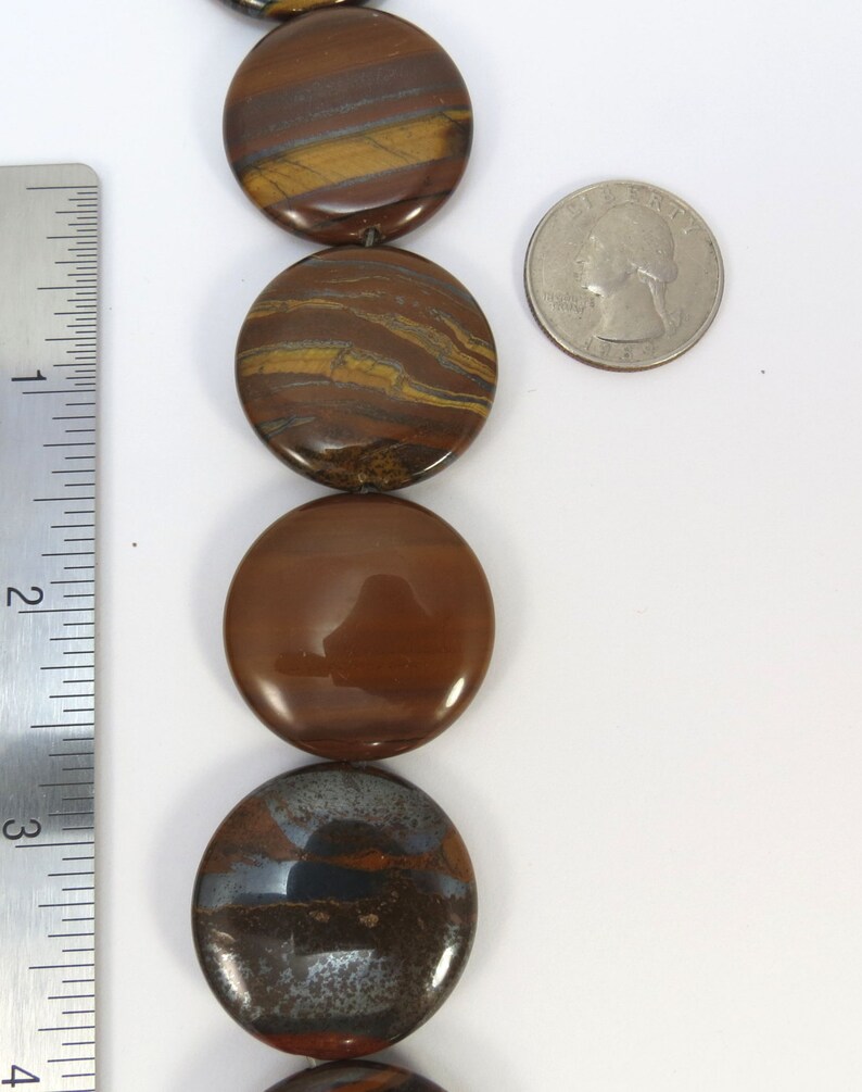 May include: A strand of round, brown and gold tiger's eye beads. The beads are approximately 2.5 cm in diameter and have a smooth, polished finish.