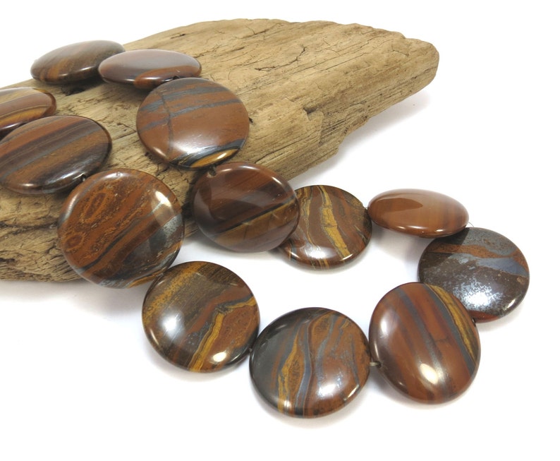 May include: A strand of round, brown and gold tiger's eye beads with silver flecks. The beads are strung on a cord and are approximately 2.5 cm in diameter.