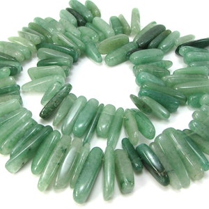 May include: A strand of green jade gemstone beads, each bead is a long, slender, and slightly irregular shape.