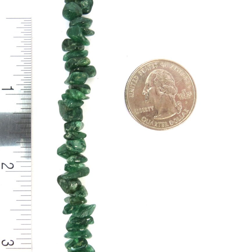 May include: A strand of green jade chip beads, approximately 5 cm long, next to a US quarter for size comparison.