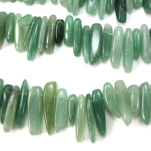 May include: A strand of light green, natural stone beads. The beads are long and narrow, with a slightly irregular shape. They are strung together on a clear thread.