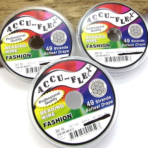 Puede incluir: Tres carretes de alambre para abalorios Accu-Flex, cada uno con una etiqueta blanca y texto negro. Las etiquetas dicen "Calidad profesional Alambre para abalorios Moda" y "49 hebras Caída más suave". Cada carrete tiene 30 pies (9,1 metros) de largo.