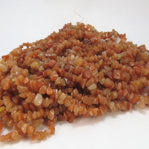 May include: A strand of small, irregular, chip-shaped carnelian beads in shades of orange, red, and brown.