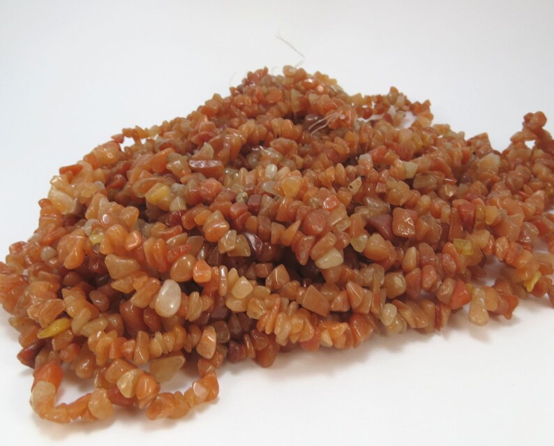 May include: A strand of small, irregular, chip-shaped carnelian beads in shades of orange, red, and brown.