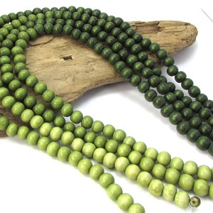 Peut inclure: Un brin de perles en bois dans des tons de vert, allant du vert clair au vert fonc&eacute;. Les perles sont rondes et lisses, et elles sont enfil&eacute;es sur un fil transparent.