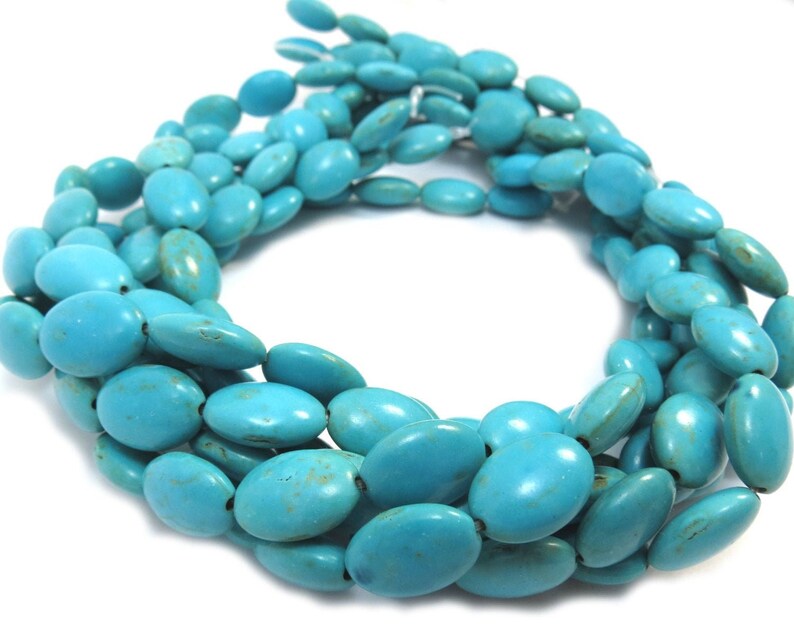 May include: A strand of oval-shaped turquoise beads. The beads are a vibrant blue-green color and have a smooth, polished finish.
