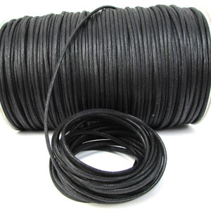 May include: A spool of black waxed cotton cord. The cord is wound tightly around the spool and is ready to be used for crafting projects.