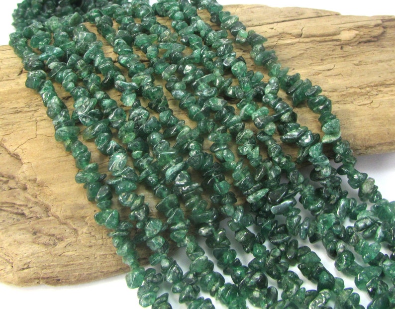 May include: A strand of green aventurine chip beads. The beads are small and irregular in shape, and they have a slightly translucent appearance.