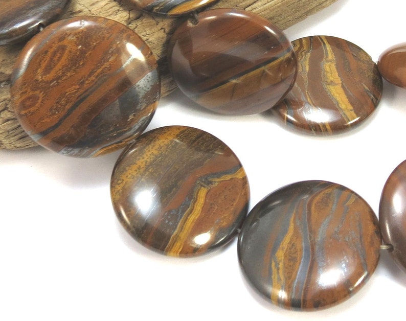 May include: A strand of round, brown and gold tiger eye beads with a metallic sheen. The beads are approximately 20mm in diameter.