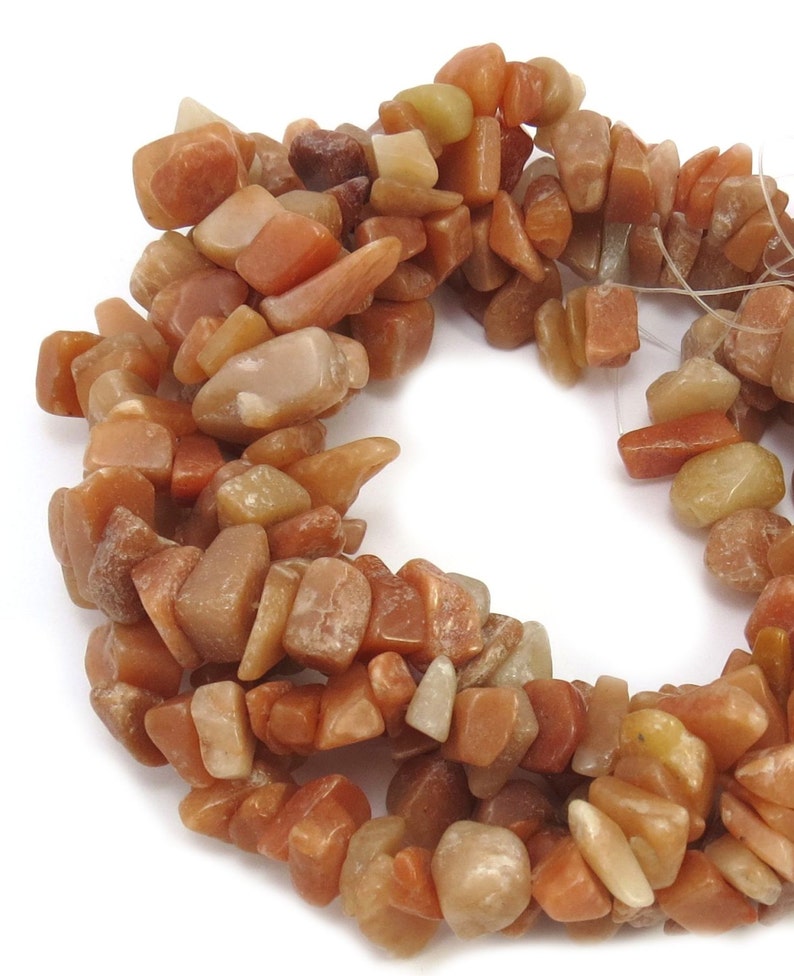 May include: A strand of orange, brown, and yellow gemstone chips. The chips are irregular in shape and have a natural, rough texture.