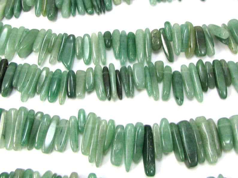 May include: A strand of green jade gemstone beads, each bead is a different shape and size, with a smooth, polished finish.
