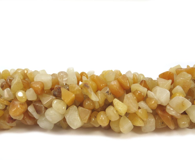 May include: A strand of yellow and white gemstone chips. The chips are irregular in shape and size, and have a smooth, polished finish.